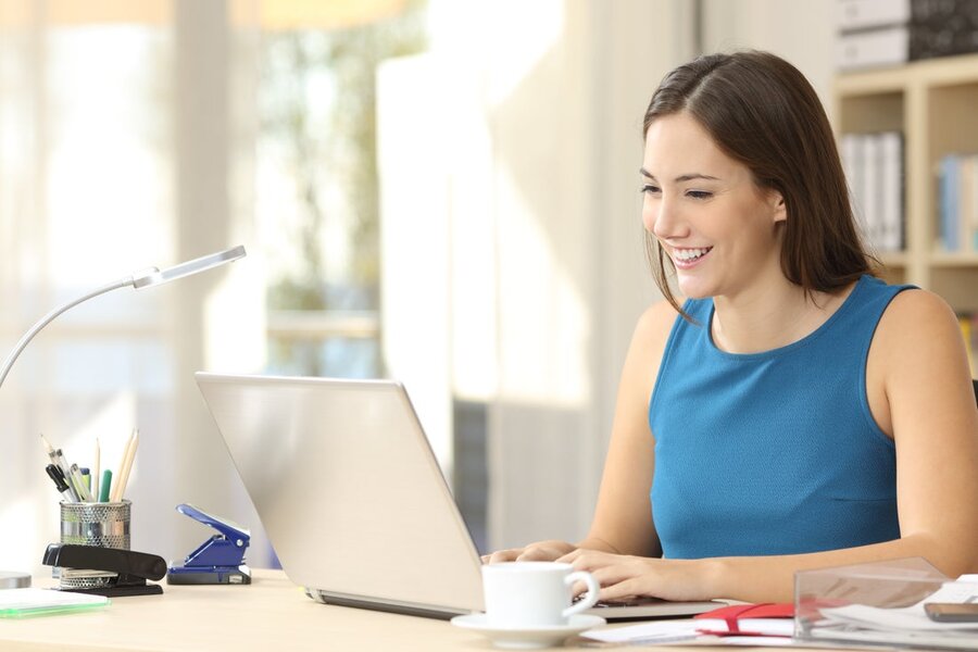 A woman at her desk and computer in her home office, utilizing her home network.