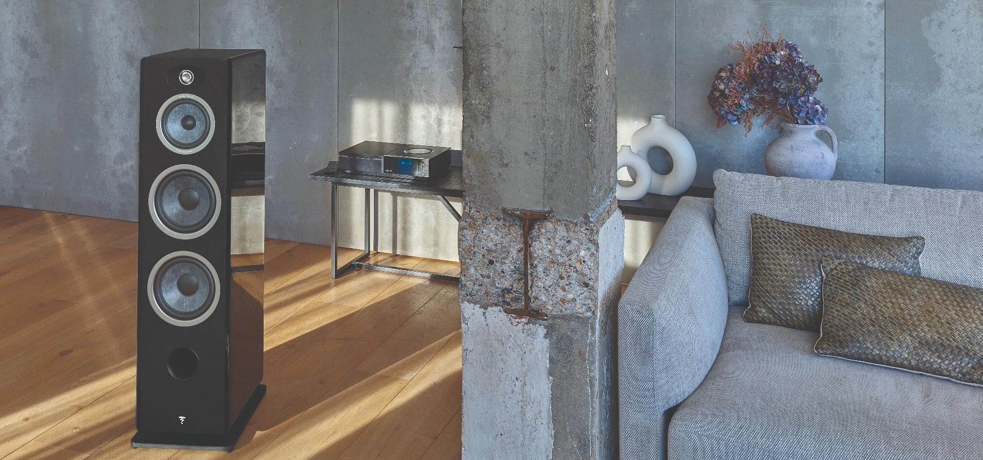 Black floorstanding speaker in modern industrial living room with gray sofa