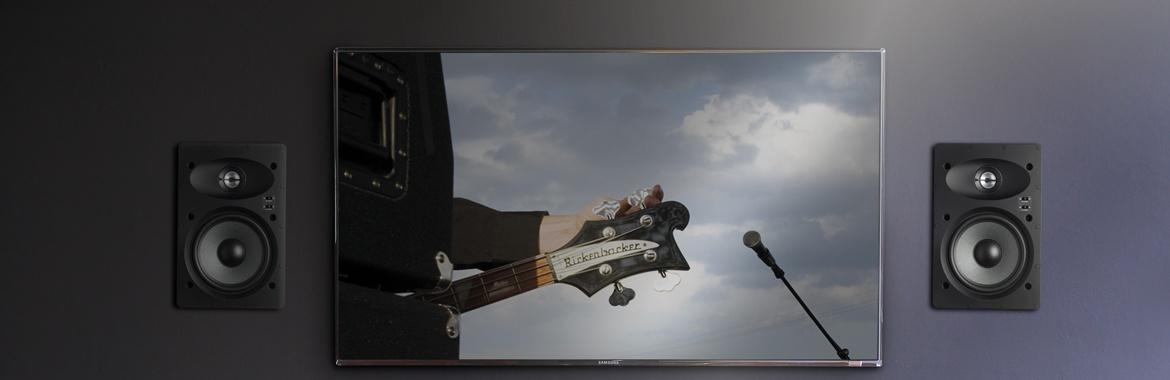 Black wall-mounted TV flanked by in-wall speakers on both sides