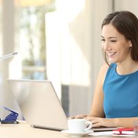 A woman at her desk and computer in her home office, utilizing her home network.