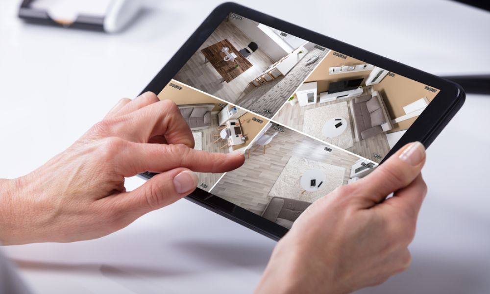 <span class="uk-h4">Hands holding a tablet with live security camera feeds.</span>