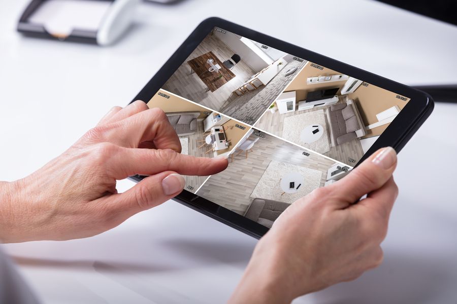 Hands holding a tablet with live security camera feeds.