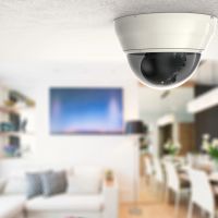 Ceiling-mounted dome security camera in a modern living and dining area, providing discreet home surveillance.
