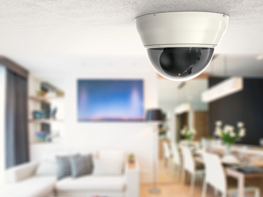 Ceiling-mounted dome security camera in a modern living and dining area, providing discreet home surveillance.